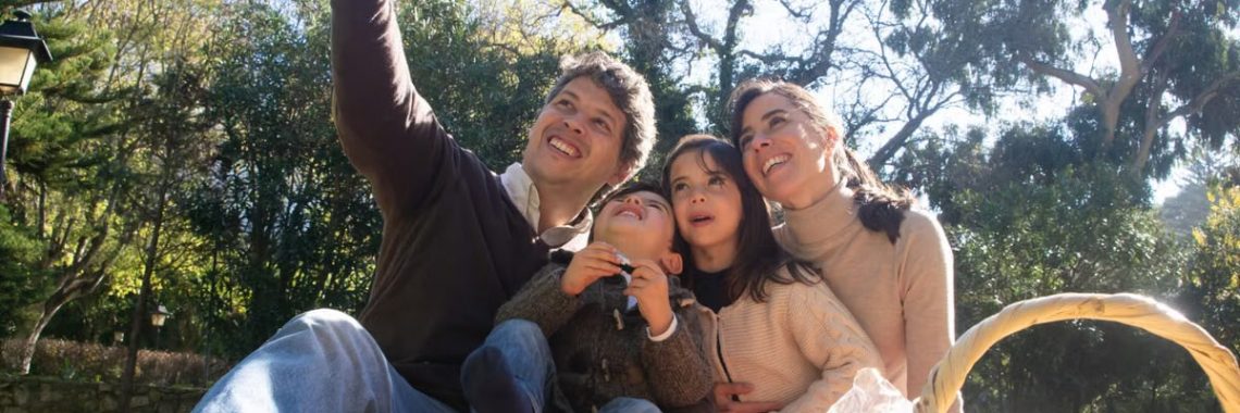 Happy family taking a selfie during a sunny picnic in a park.