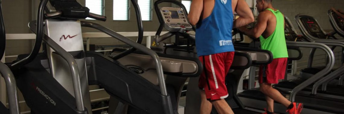 Two men running on treadmills in a modern gym, promoting fitness and health.